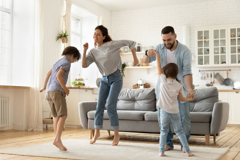 Happy family dancing to music in the living room